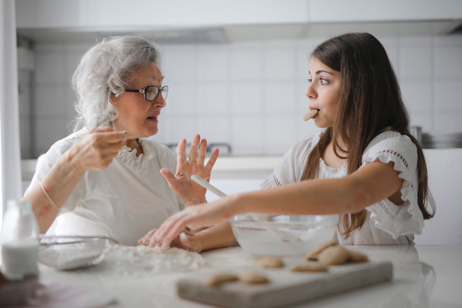 A grandmother and granddaughter baking together in a bright kitchen